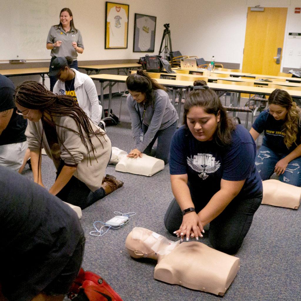 在心肺复苏术课上，学生们趴在人体模型前面的地板上.